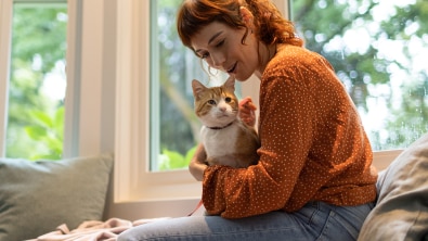 donna con maglione arancione che tiene un gatto